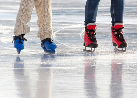 Close-up of red and blue ice skates gliding across a sunlit rink