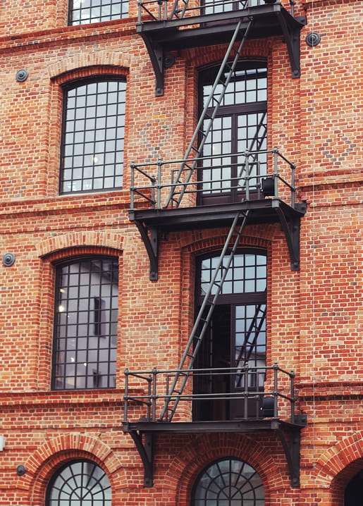 Red brick facade with arched windows and a zigzagging iron fire escape