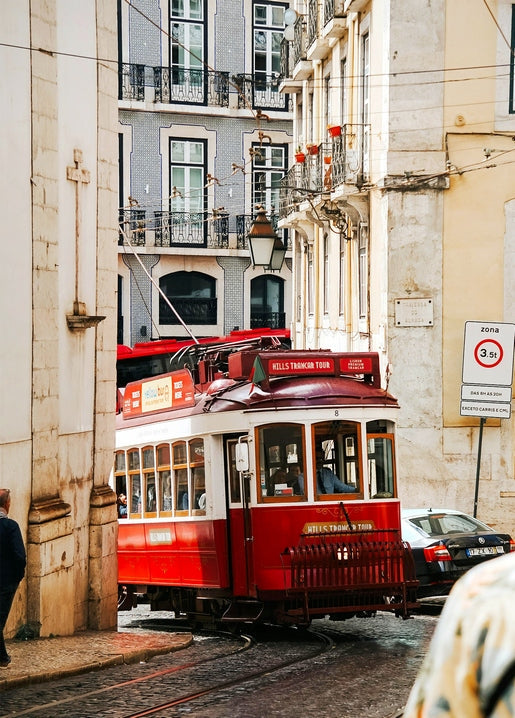 Rote Straßenbahn auf einer Kopfsteinpflasterstraße in Lissabon