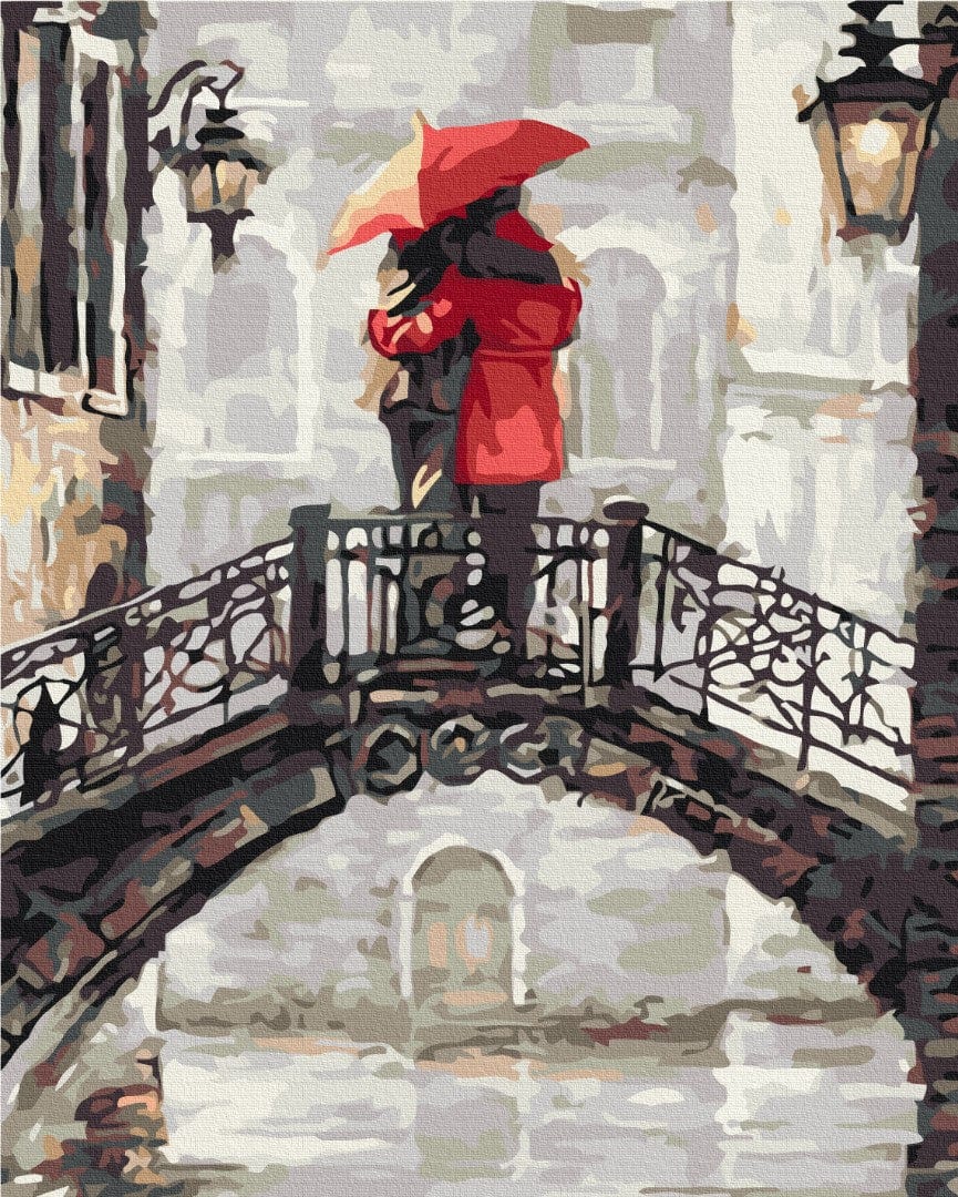 Paar umarmt sich unter einem roten Regenschirm auf einer alten Bogenbrücke im Regen