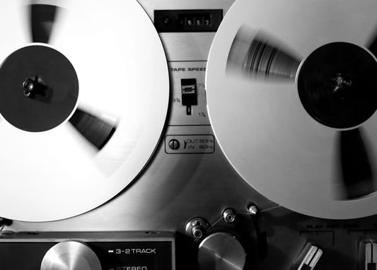 Close-up of a reel-to-reel tape recorder with two spinning tape spools, black-and-white postcard.