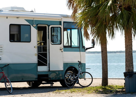Türkis-weißes Vintage-Wohnmobil am Meer mit Fahrrädern und Palmen