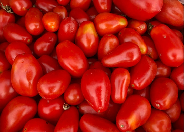 Close-up macro photo of ripe red plum tomatoes with glossy skins