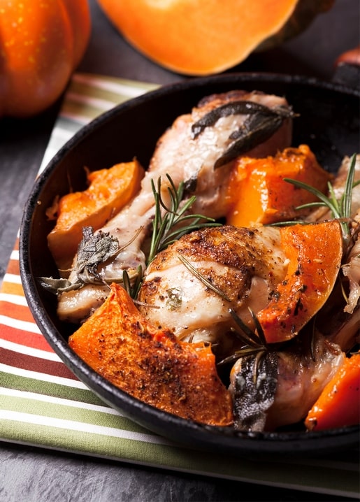 Gebratenes Hähnchen mit karamellisiertem Kürbis, Salbei und Rosmarin in einer Gusseisenpfanne