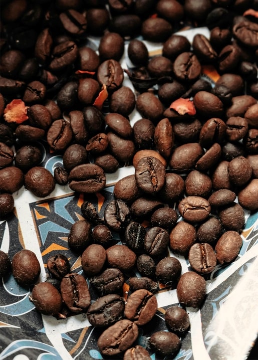 Geröstete Kaffeebohnen verstreut auf einem gemusterten Keramiktablett
