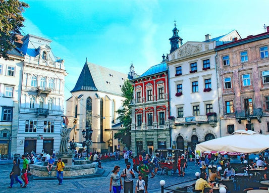 Colorful historic façades and church tower on Rynok Square, Lviv, filled with people