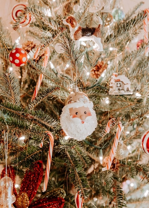 Glass Santa ornament among candy canes and lights on a Christmas tree