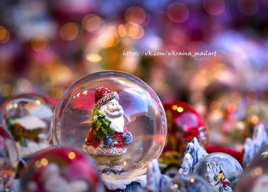 Winzige Weihnachtsmann-Figur in einer gläsernen Schneekugel umgeben von warmem Lichterglanz