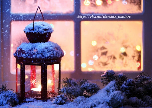Schneebedeckte Laterne mit brennender Kerze vor einem raureifbedeckten Fenster mit Lichterbokeh