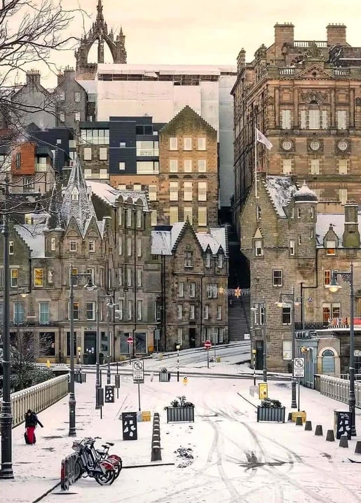 Snow-covered old town street with historic stone buildings and parked bicycles