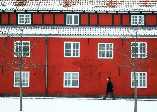Red townhouse with snow-dusted roof and a person walking past