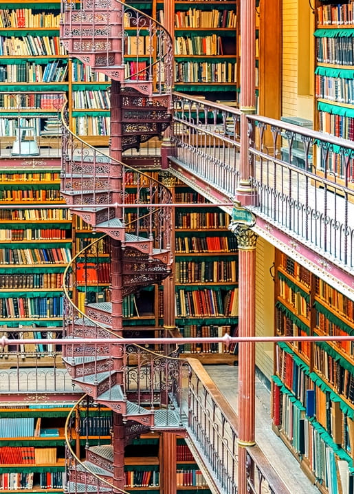 Bibliotheksatrium mit schmiedeeiserner Wendeltreppe und mehreren Reihen Bücherregalen