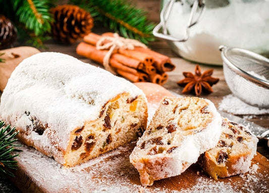 Sliced Christmas stollen dusted with powdered sugar next to cinnamon sticks and star anise