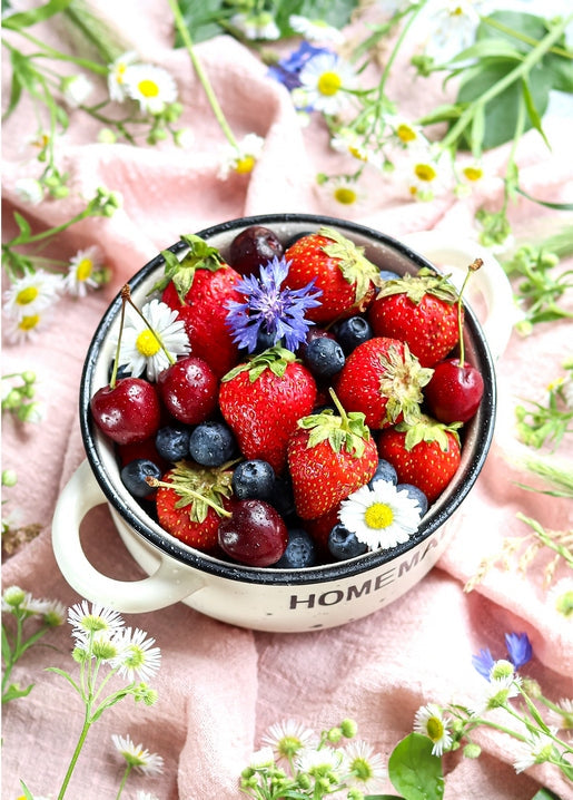 Емальована миска з написом «Homemade», повна полуниці, чорниці, вишень, ромашок і волошок