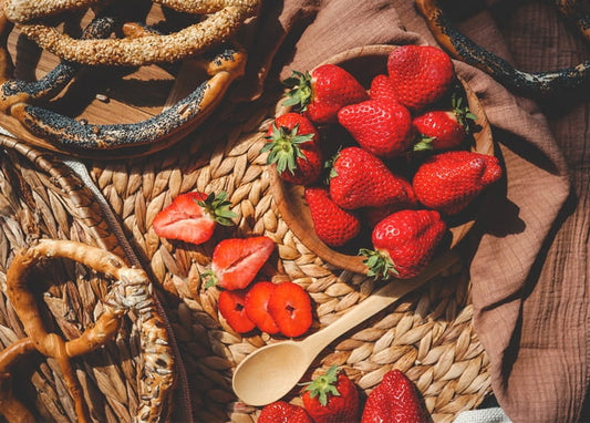 Frische Erdbeeren in einer Holzschale neben Sesambrezeln auf einem Untersetzer