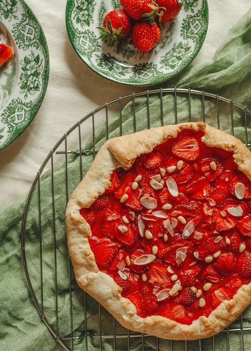 Erdbeer-Galette auf einem Kuchengitter neben Vintage-Tellern mit Beeren