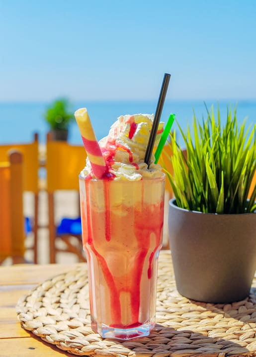 Erdbeer-Milchshake mit Sahne auf einem Café-Tisch am Meer