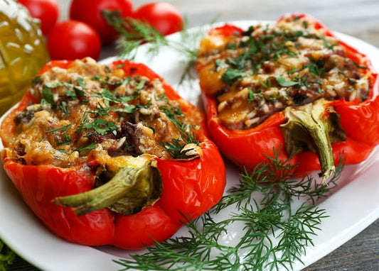 Zwei mit Reis gefüllte Paprika, überbacken mit Käse und Dill