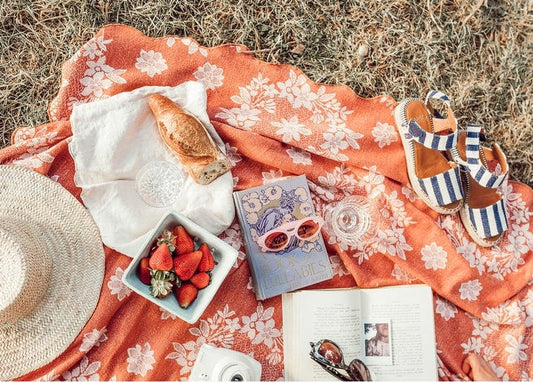 Summer picnic flat lay with strawberries, bread, a straw hat and striped sandals