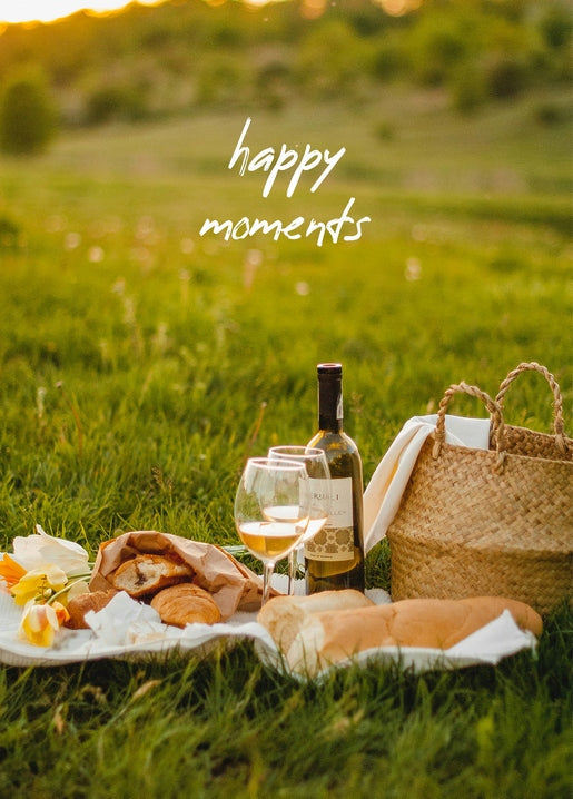 Sunset picnic with wine, bread, a wicker basket, and tulips on a white blanket