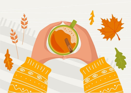 Sweater-clad hands cupping a mug of spiced autumn tea with a cinnamon stick