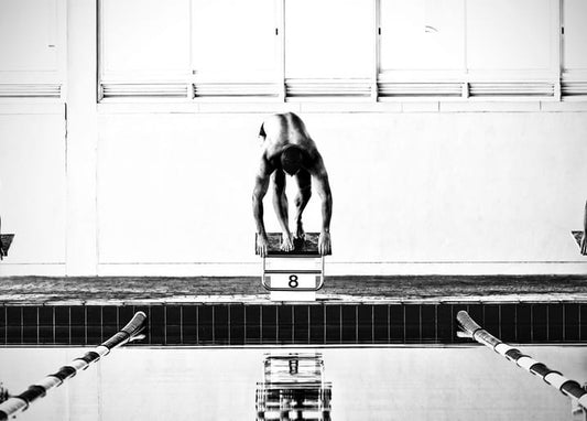 Swimmer crouched on starting block number eight, seconds before diving into the pool