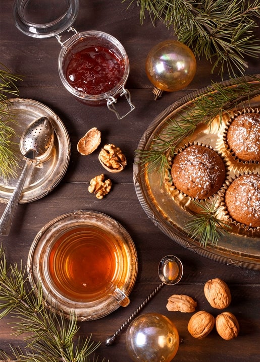 Amber tea, jam, walnuts and powdered gingerbread muffins on dark wood
