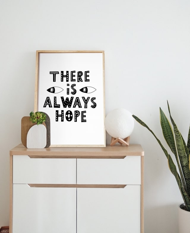 ‘There is always hope’ poster displayed on a dresser with a moon lamp and snake plant
