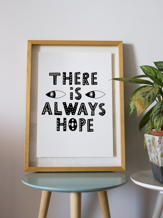 Framed ‘There is always hope’ poster leaning against a wall beside a potted plant