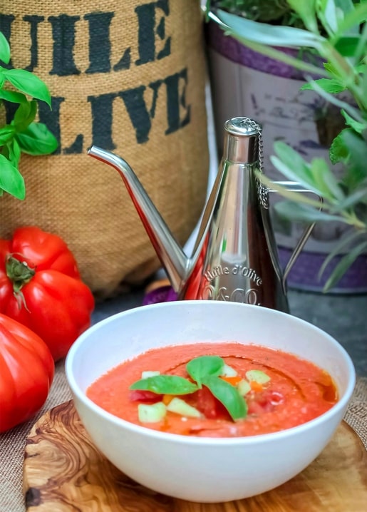 Bowl of chilled tomato gazpacho with basil, tomatoes and olive-oil dispenser