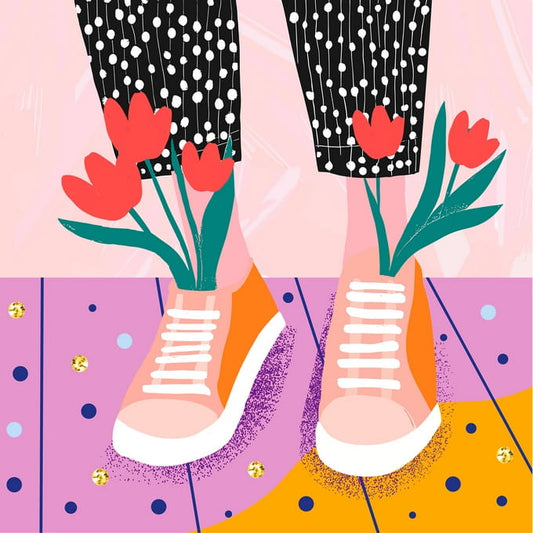 Rote Tulpen wachsen aus rosa Sneakers auf einem mit Konfetti bedeckten Boden