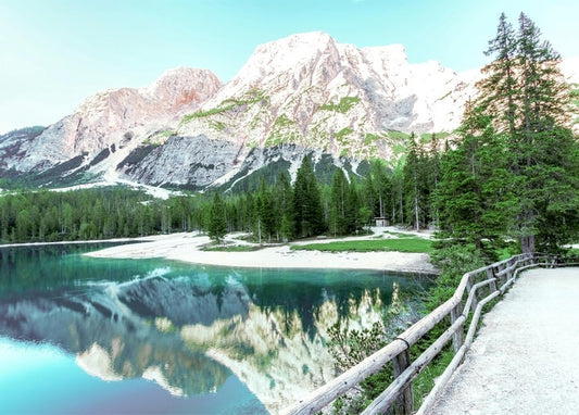 Turquoise alpine lake reflecting snow-capped mountain peaks and pine forest