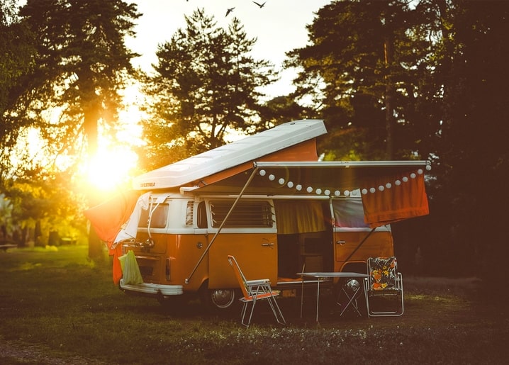 Vintage-VW-Campingbus mit Markise und Lichterkette im Sonnenuntergang