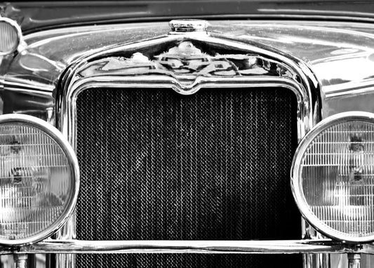 Close-up of a vintage car's chrome grille and round headlights, black and white