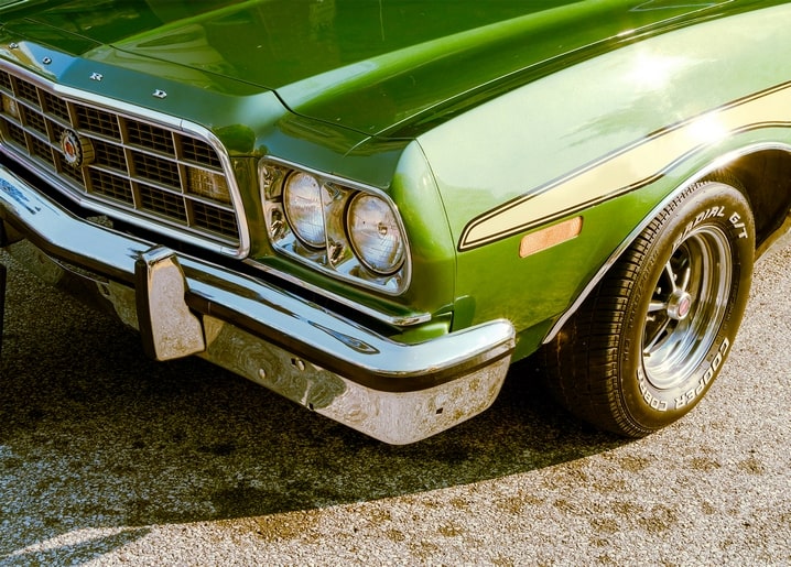 Chromgrill und runde Scheinwerfer eines grünen Oldtimer-Autos