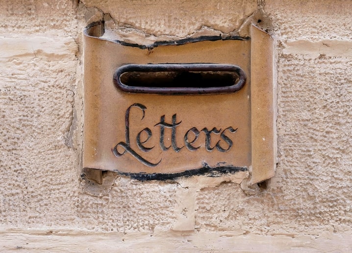 Verwitterte Steinwand mit Briefeinwurf und dem handgeschnitzten Wort Letters