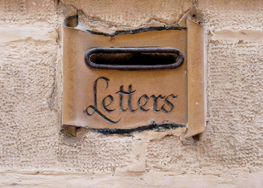 Verwitterte Steinwand mit Briefeinwurf und dem handgeschnitzten Wort Letters