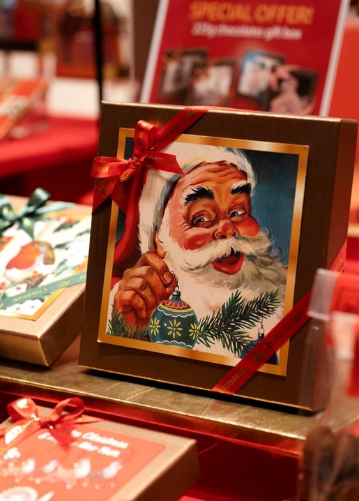 Vintage-style Santa Claus illustration on a red-ribboned gift box in a festive shop display
