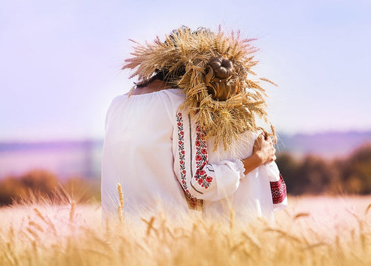 Woman and girl in embroidered vyshyvanka shirts with wheat wreaths, embracing in a wheat field