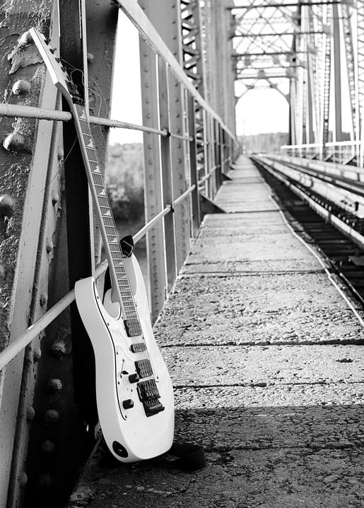 Weiße E-Gitarre lehnt an einem Stahlträger auf einer Eisenbahnbrücke