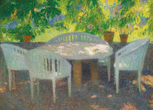 White wicker chairs and table in dappled sunlight under garden foliage at Marquayrol