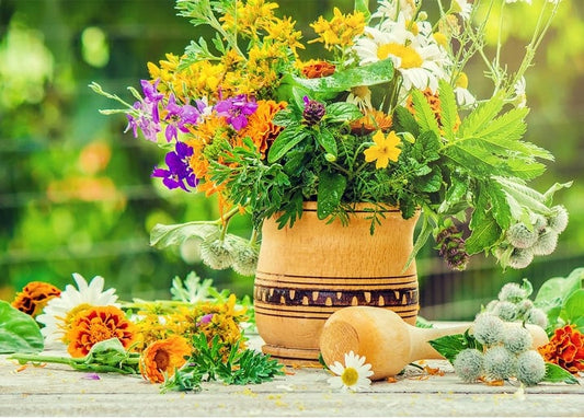 Wooden mortar filled with marigolds, daisies and purple wildflowers on a garden table