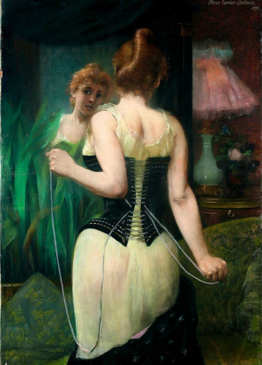 Rothaarige Frau im hellen Unterkleid schnürt vor dem Spiegel ihr schwarzes Korsett