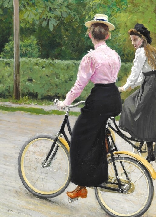 Woman in a pink blouse cycling down a park path with a friend in white close behind