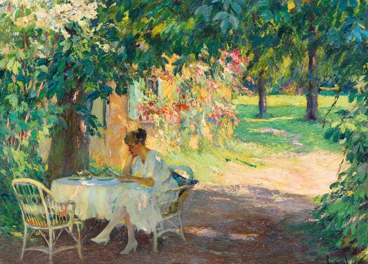 Woman reading at a wicker table in the blossoming garden of an artist's villa on Lake Starnberg