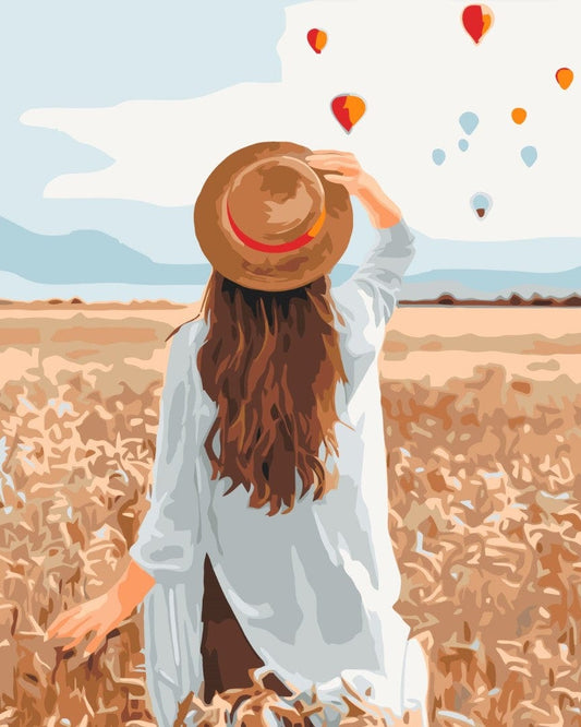 Frau von hinten mit Hut geht durch ein goldenes Roggenfeld, am Himmel Heißluftballons, Malen-nach-Zahlen-Bild