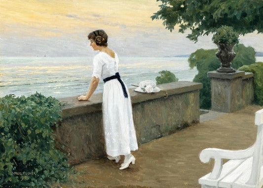 Woman in a white dress leaning on a stone terrace balustrade, gazing at the sea at sunset