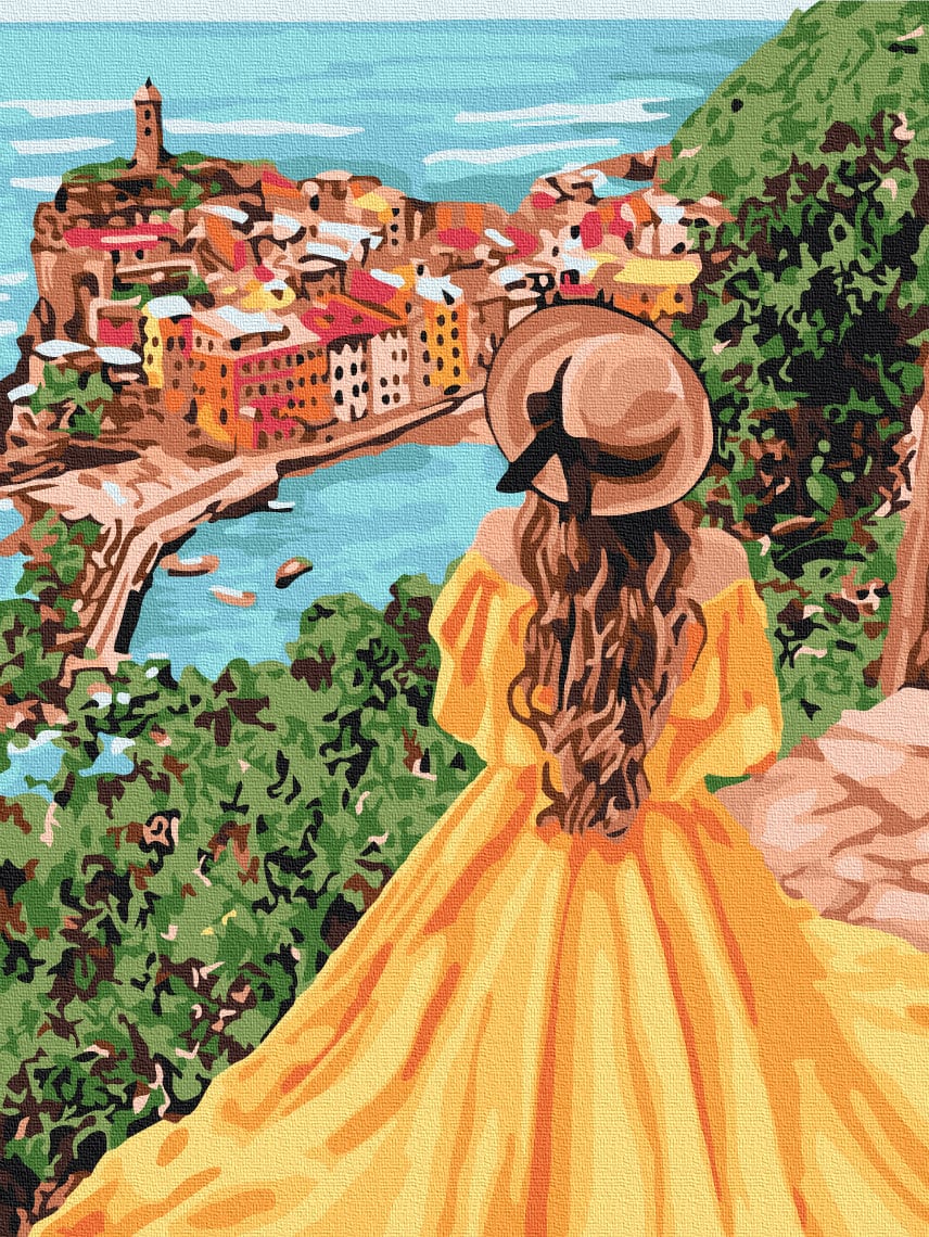 Frau in Sonnenhut und goldenem Kleid blickt von einer Klippe auf ein buntes Küstenstädtchen