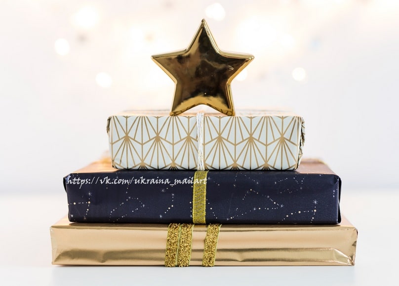 Gestapelte Weihnachtsgeschenke in goldenem und marineblauem Papier mit goldenem Stern obenauf
