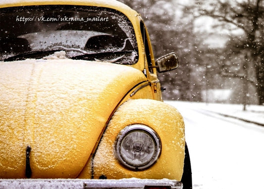 Gelber Volkswagen Käfer dick mit Schnee bedeckt bei Schneefall auf verschneiter Straße